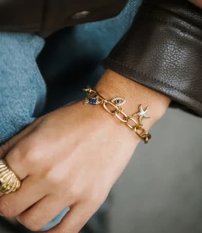 Bracelet à charms — œil porte-bonheur et étoile de mer sertie — porté au poignet