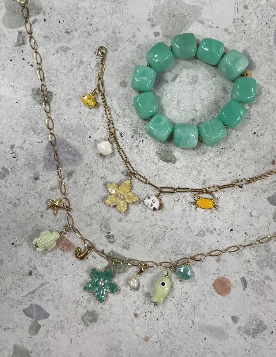 Colliers à charms et bracelet de perles vertes assortis, posés côte à côte